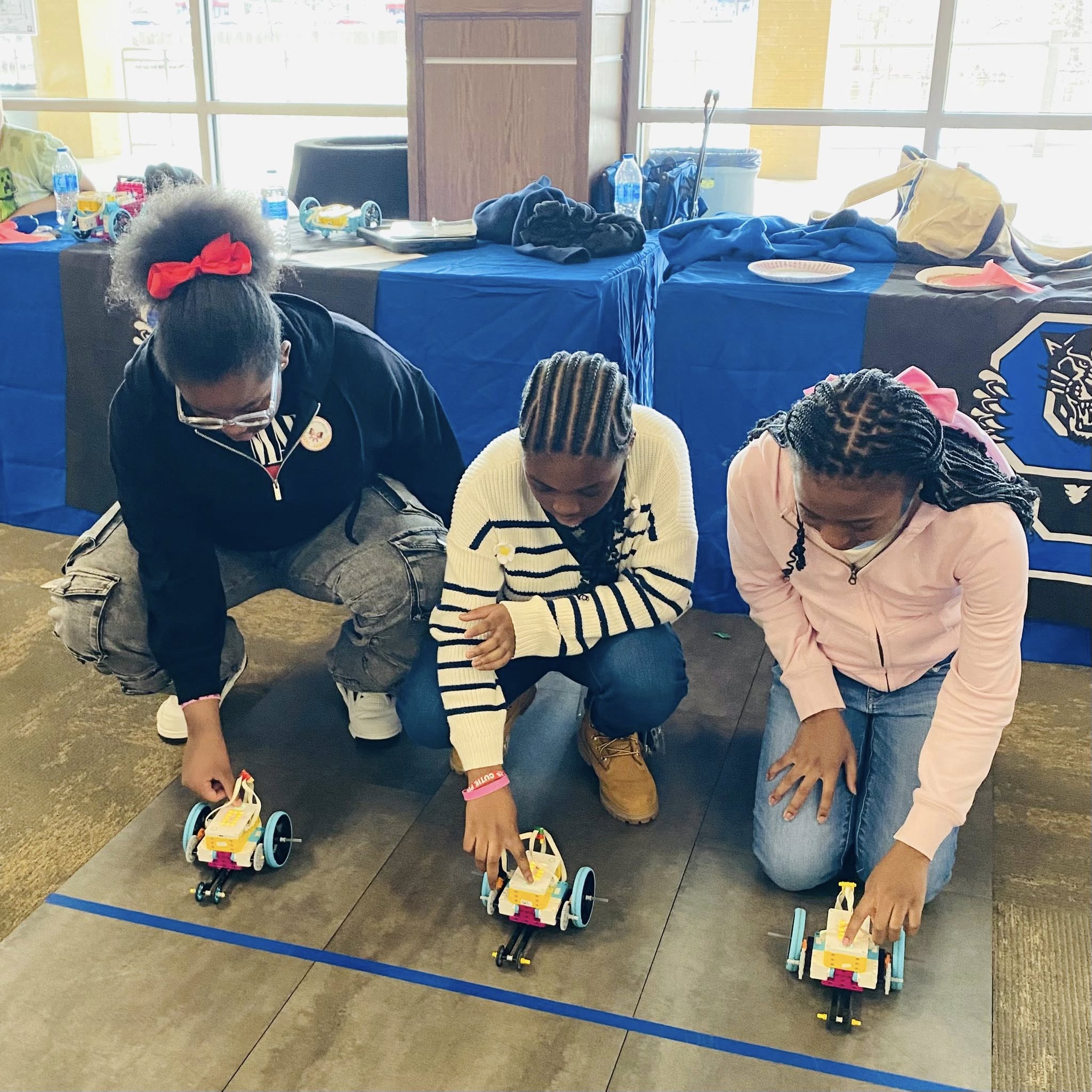 Three girls each with a Lego car.